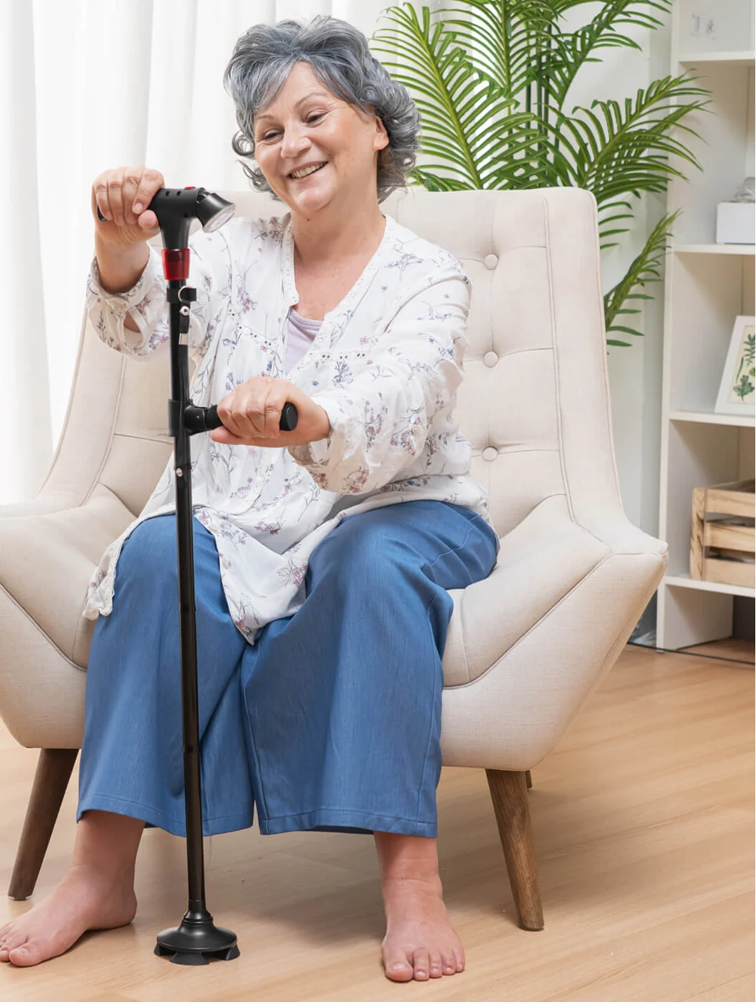 A woman seated in an armchair holding both handles of the Ready Walker